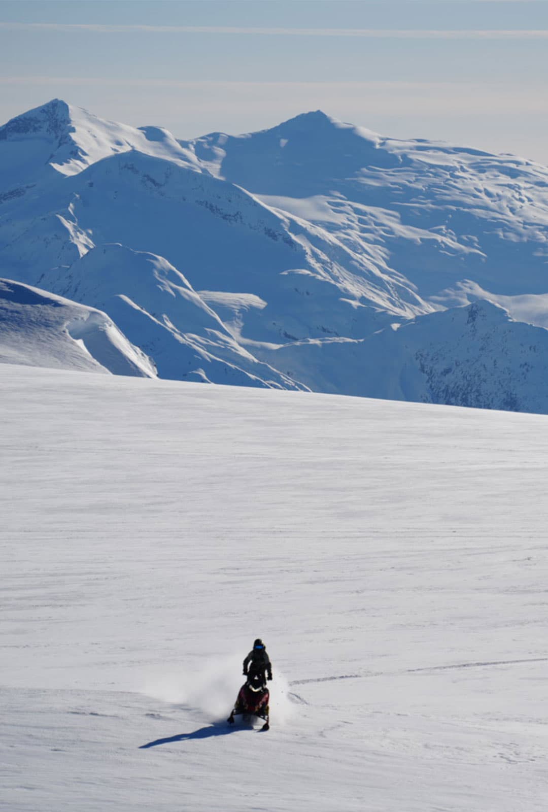 Rider crossing an open alpine bowl below Brandywine